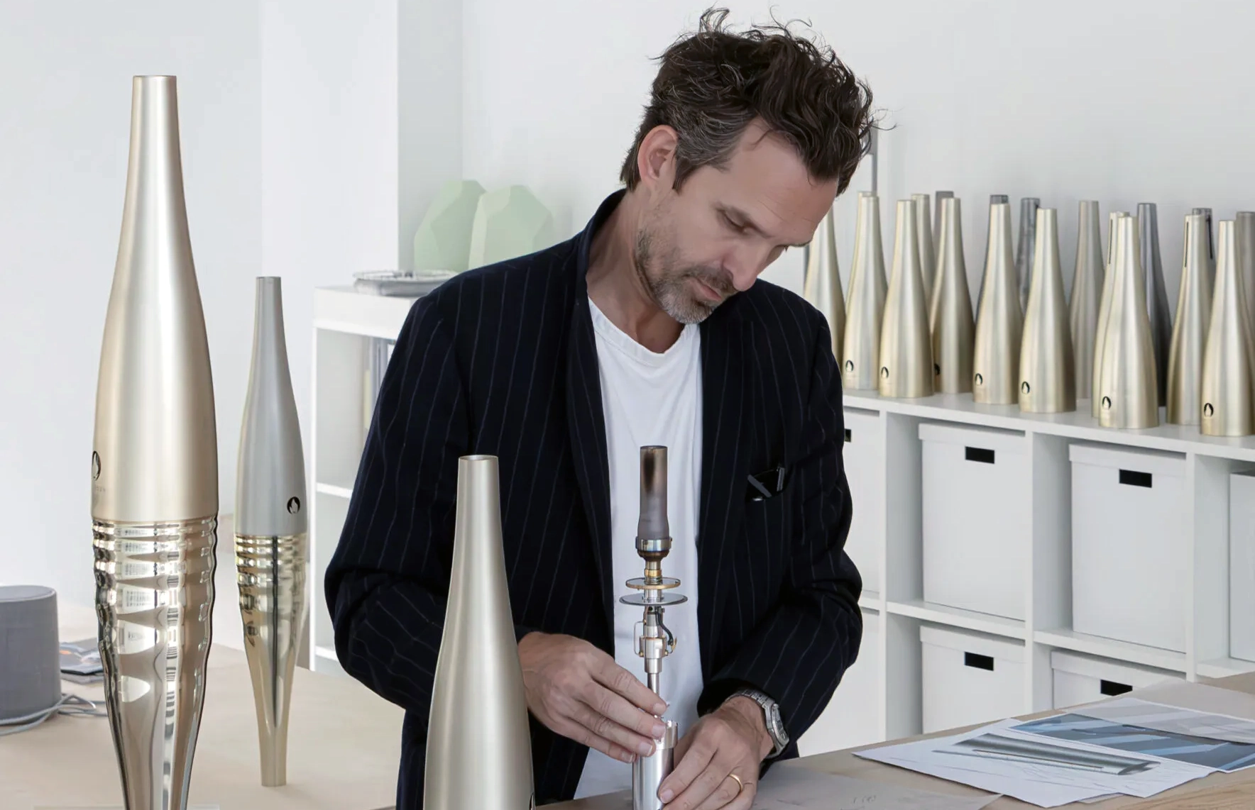 Le designer Mathieu Lehanneur en train de monter le système d'inflammation de la torche olympique dans son atelier de design (nombreuses torches stockées autour de lui). 